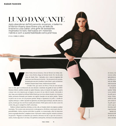 A photo of an article published by Forbes about the brand Studio DRÈA, its history, and founders. There is black text in a white background and a photo of a model wearing black and holding a powder pink violette leather handbag from Studio DRÈA while standing on a ballet bar.